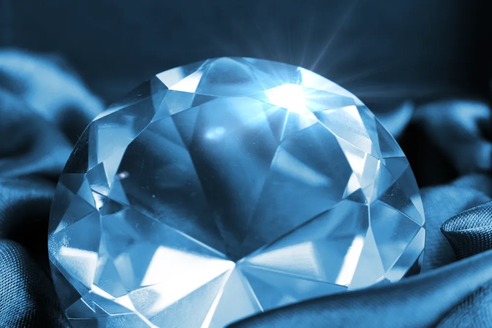 Großer blauer SI1 Diamant liegt auf elegantem Stoff und reflektiert Licht mit strahlender Brillanz